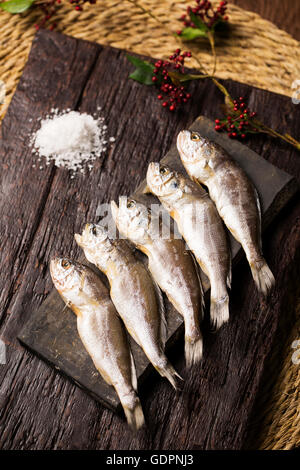 Dried Corvina on Rustic Board with Salt and Tree Branches on the Side Stock Photo