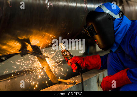 Welder in factory welding metal pipes Stock Photo