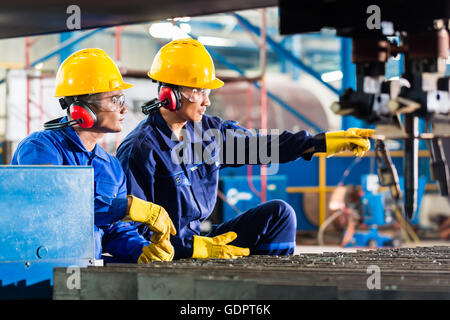 Worker in Asian factory at industrial metal cutting torch machine Stock Photo