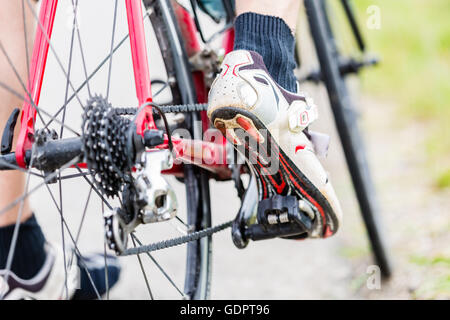 Chain, pedal, rear wheel and sprocket of bike, detail, man having foot on pedal Stock Photo