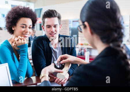 Optician handing new glasses to couple, woman and man, in her shop Stock Photo