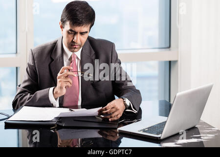Indian Senior Executive in his skyscraper office, reading business contracts Stock Photo