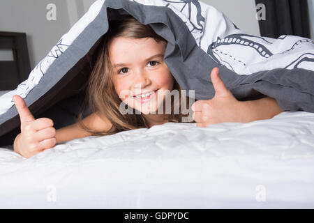 Child or teen under covers in bed Stock Photo