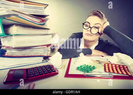 Health concept at business work. Tired overworked young businesswoman secretary manager. Sick ill young female sleeping at workplace. Stock Photo