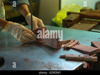 Worker cutting tuna in tsukiji fish market, Kanto region, Tokyo, Japan
