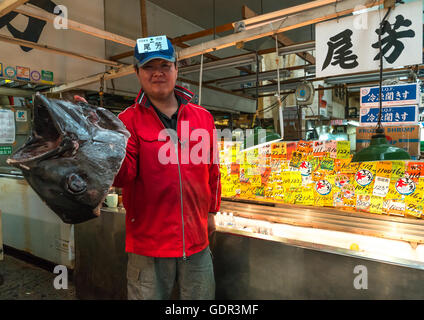 Vendor holding a big tuna fish in tsukiji fish market, Kanto region, Tokyo, Japan