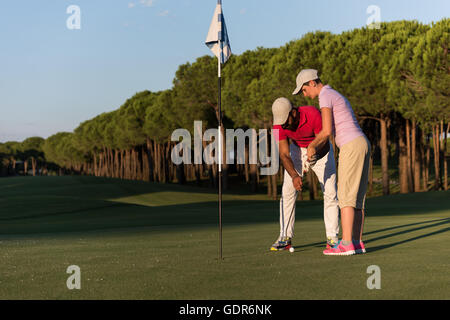 male golf instructor teaching female golf player, personal trainer giving lesson on golf course Stock Photo