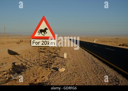 Road through the desert with a warning sign Attention horses, near Aus, Karas Region, Namib, Namibia Stock Photo