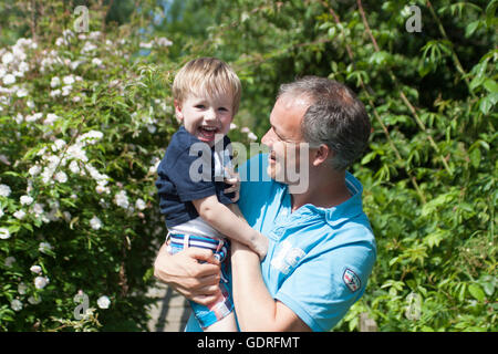 Boy, 2 years, with big smile being held and tickled by his father, Netherlands Stock Photo