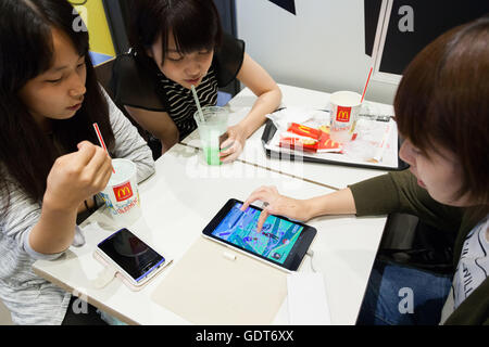 Tokyo, Japan. 22nd July, 2016. Fans try out Pokemon Go at McDonald's Shinjuku branch on July 22, 2016, Tokyo, Japan. The Pokemon Go app finally arrived in the land of the Pokemon on Friday 22, July two weeks after its launch in the United States. The release of the app in Japan had been rumoured for the past few days after the leak of details of a partnership deal with McDonald's Japan to create Pokemon Gyms in its 3,000 locations. Nintendo's market value has almost doubled since the app created by Niantic first launched in America. © Rodrigo Reyes Marin/AFLO/Alamy Live News Credit:  Aflo Co.  Stock Photo