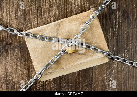 Old book with chain and padlock on wooden background. Stock Photo