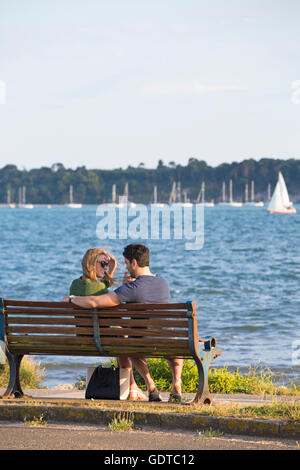 Couple sitting on bench by the sea at Baiter, Poole in July Stock Photo