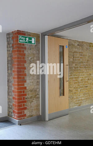 Modern fire door in a new extension to a Victorian school. New door adjoins original brickwork and features latest trap-free hinges Stock Photo