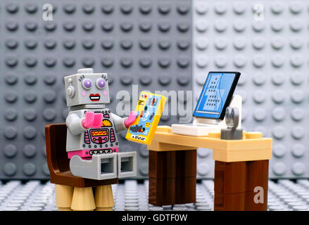 Tambov, Russian Federation - July 06, 2016 Lego robot minifigure with instruction sitting near computer. Stock Photo