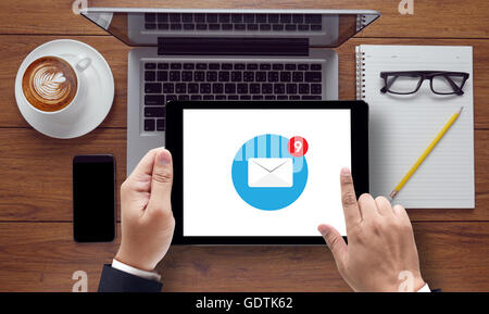 email icon on tablet pc screen held by businessman hands - concept, top view computer, phone ,coffee, Warm tone Stock Photo