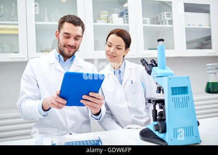 scientists with tablet pc and microscope in lab Stock Photo