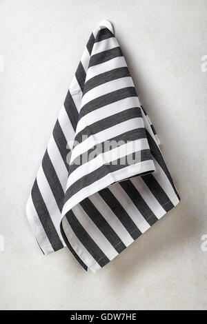 Black and white striped towel hanging on white concrete wall background Stock Photo