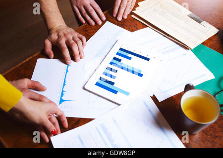 Business team hands at work with financial reports and a tablet computer, top view Stock Photo