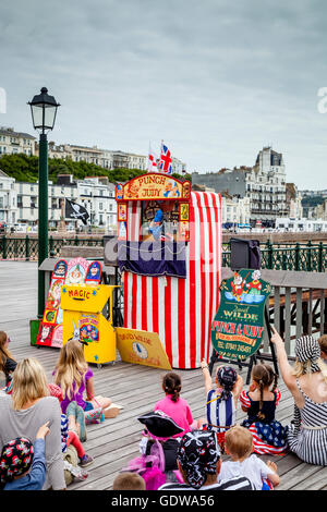 People Watch A Traditional Punch and Judy Show On Hastings Pier, Hastings, Sussex, UK Stock Photo