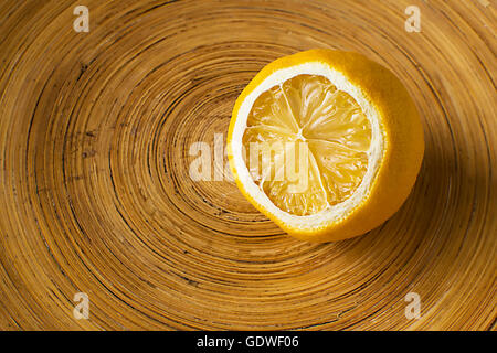 Lemon in Wooden Bowl. Mild Dried Lemon on Wooden Background. Half of a Yellow Lemon Stock Photo