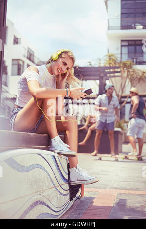 Young woman with headphones and mp3 player listening to music with surfboard Stock Photo