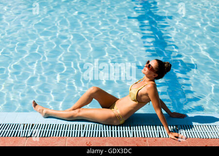 Young woman sitting near swimming pool Stock Photo