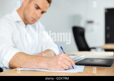 Concentrated young businessman sitting and writing at the table Stock Photo