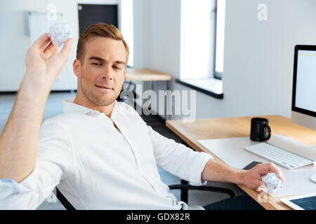 Handsome young businessman crumpling and throwing paper in office Stock Photo