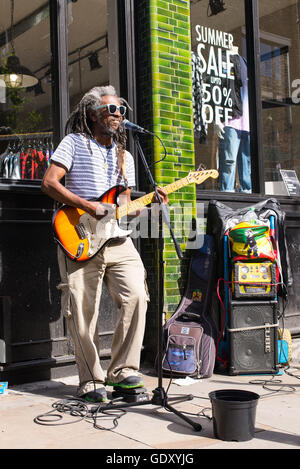 Busker musician artist with afro style dreadlocks hair playing electric guitar and singing in Brick Lane Stock Photo