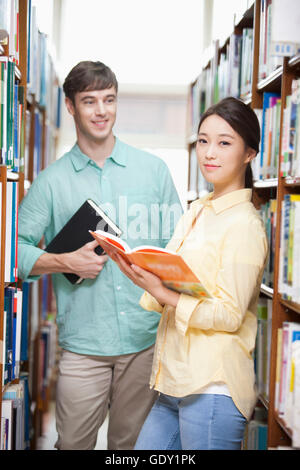 Young smiling college students with books at library Stock Photo - Alamy