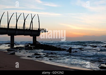 Man performing religious ritual next to the Millennium Pier in Umhlanga Rocks at Sunrise, with ships on the Indian Ocean in the Stock Photo