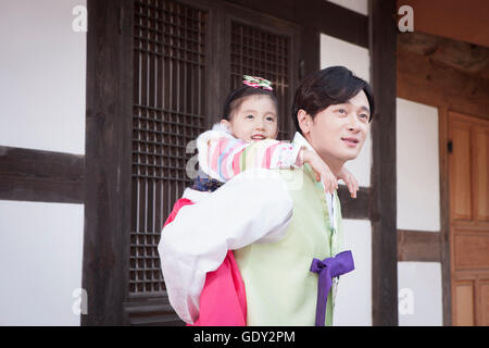 Smiling father carrying his daughter on his back on traditional Korean holiday Stock Photo