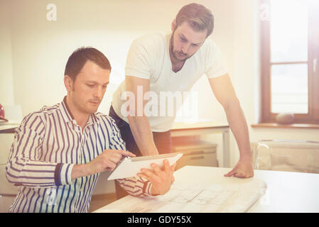 Architects discussing about project on digital tablet in the office, Bavaria, Germany Stock Photo