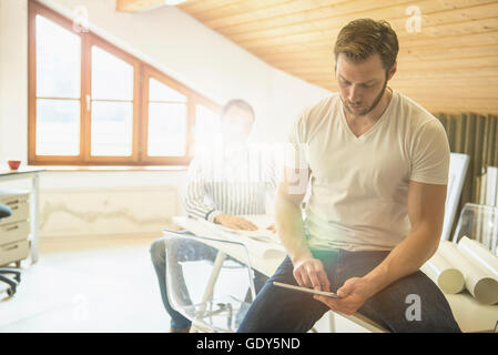 Architect working on digital tablet with his Colleague in background, Bavaria, Germany Stock Photo