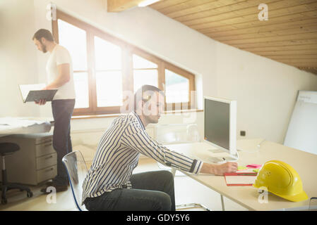 Architect doing paperwork and working on computer in office, Bavaria, Germany Stock Photo