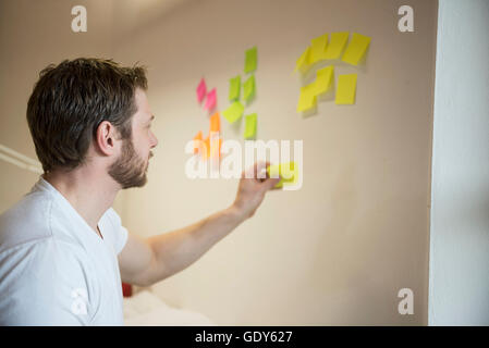 businessman sticking adhesive notes on wall, Bavaria, Germany Stock Photo