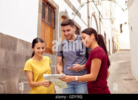 Tourist couple on vacation with a backpack and map asking for directions in a narrow street while dressed casually in jeans and  Stock Photo