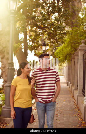 Young couple strolling leisurely down a road sightseeing, smiling happily while dressed casually in jeans and t-shirts Stock Photo