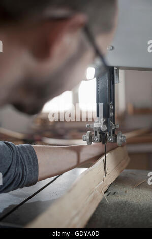 Male bow maker sawing wood with a bandsaw, Bavaria, Germany Stock Photo