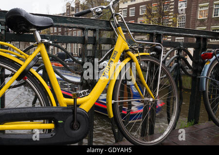 AMSTERDAM - NOVEMBER 15, 2015: Yellow rental bike on a bridge. The number of bicycles equal the number of residents in the dutch Stock Photo