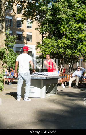 Two young men playing table tennis in a brightly lit Soho Square in London's West End, UK Stock Photo