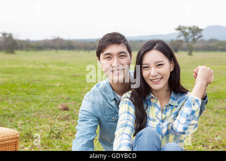 Portrait of young smiling couple in field having picnic Stock Photo
