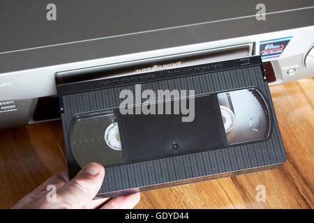 mans hand inserting VHS blank cassette tape in a VHS player Stock Photo