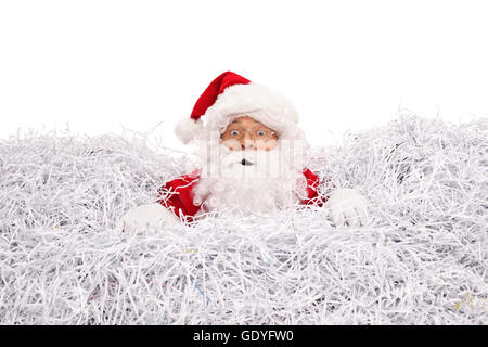 Confused Santa Claus drowning in a pile of shredded paper isolated on white background Stock Photo