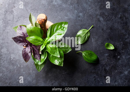 Fresh garden basil herbs in mortar on stone table. Top view Stock Photo