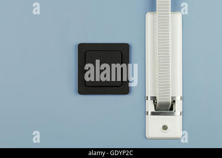 shutter belt and light switch,on blue wall Stock Photo