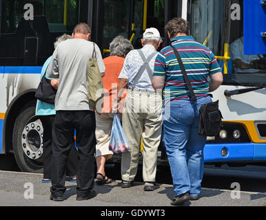 People getting in to the bus at the bus stop Stock Photo