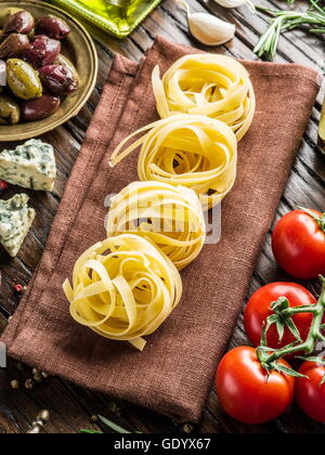Pasta ingredients. Cherry-tomatoes, spaghetti pasta, rosemary and spices on the wooden table. Stock Photo