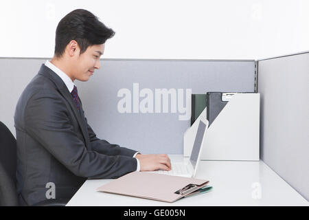Side view portrait of young smiling man using a notebook computer at work Stock Photo