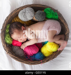Cute newborn baby girl sleeping with ball of wools in basket, Fürstenfeldbruck, Bavaria, Germany Stock Photo